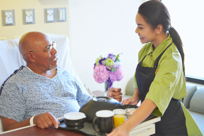 caregiver serving food to a senior man