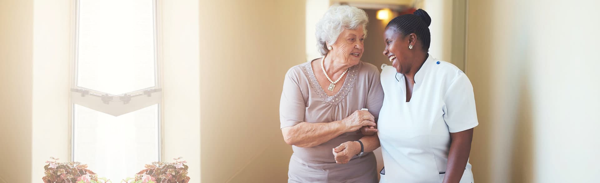 elderly woman and caregiver talking while walking happily
