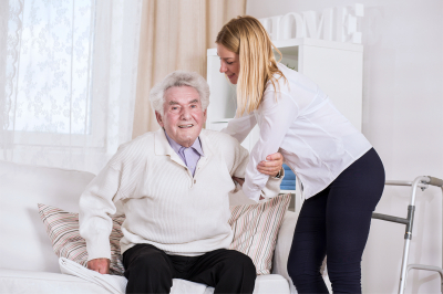 young female care assistant helping senior man